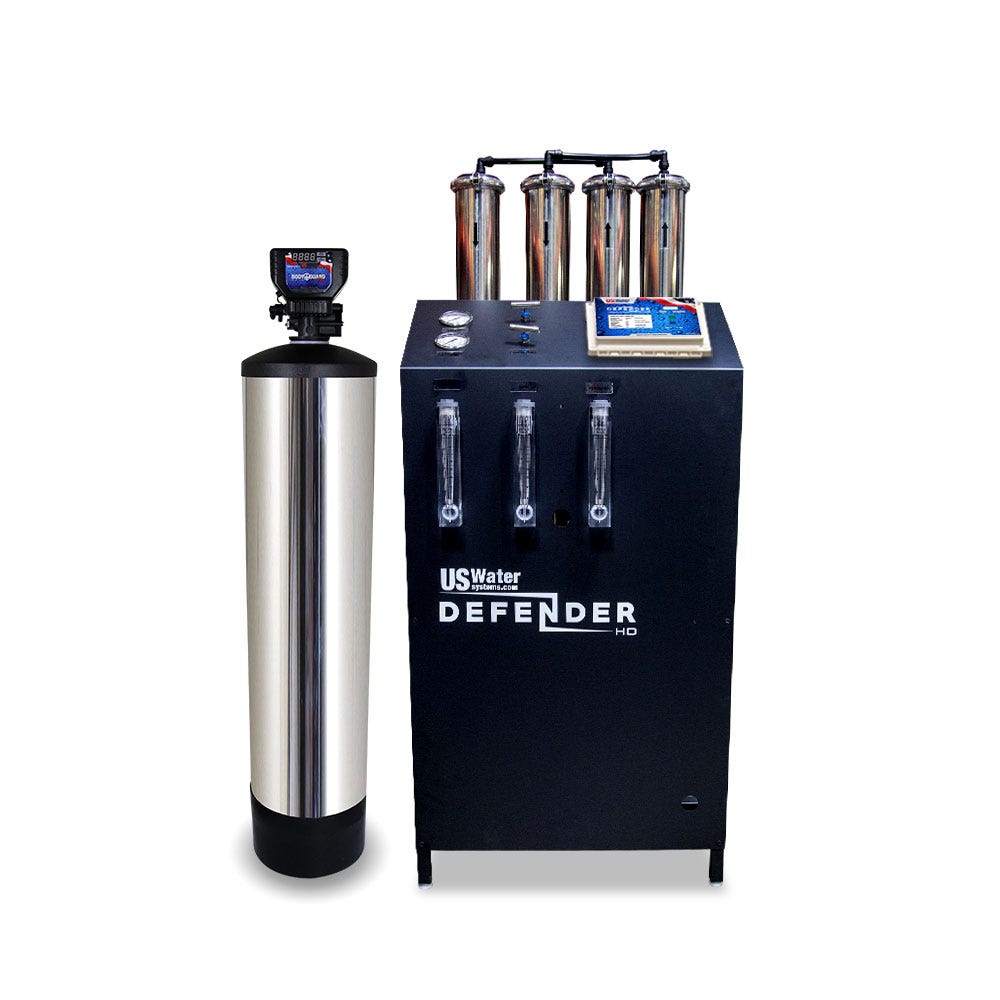 The eco-friendly Defender Commercial RO System by US Water Systems Inc features a tall cylinder on the left and a larger rectangular unit on the right with multiple gauges and monitors for efficient water filtration, processing 2000 - 16000 gallons per day.