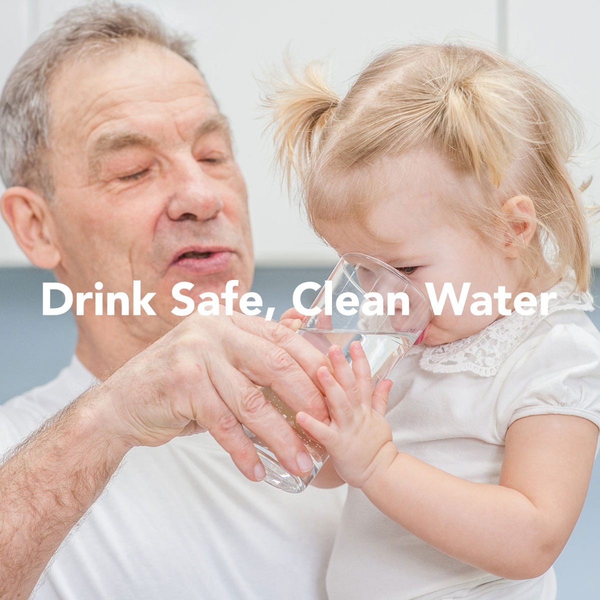 An older man assists a child drinking from a glass, showcasing the American quality of safe hydration. Drink Safe, Clean Water is the reassuring text, supported by US Water Systems American-Made 6 Stage Alkaline Reverse Osmosis System.